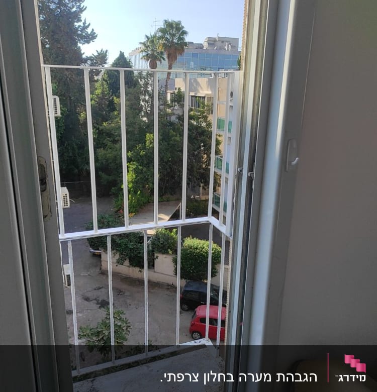 חלון פתוח עם סורגי מתכת לבנים